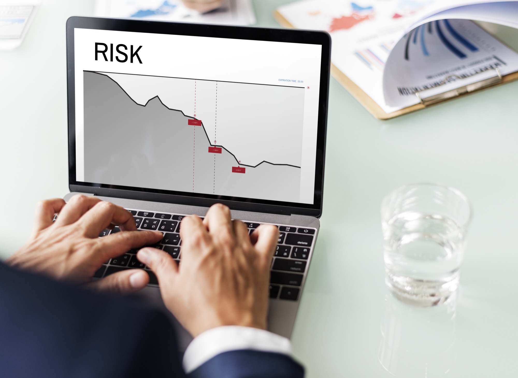 Hands typing on a laptop displaying a business risk graph