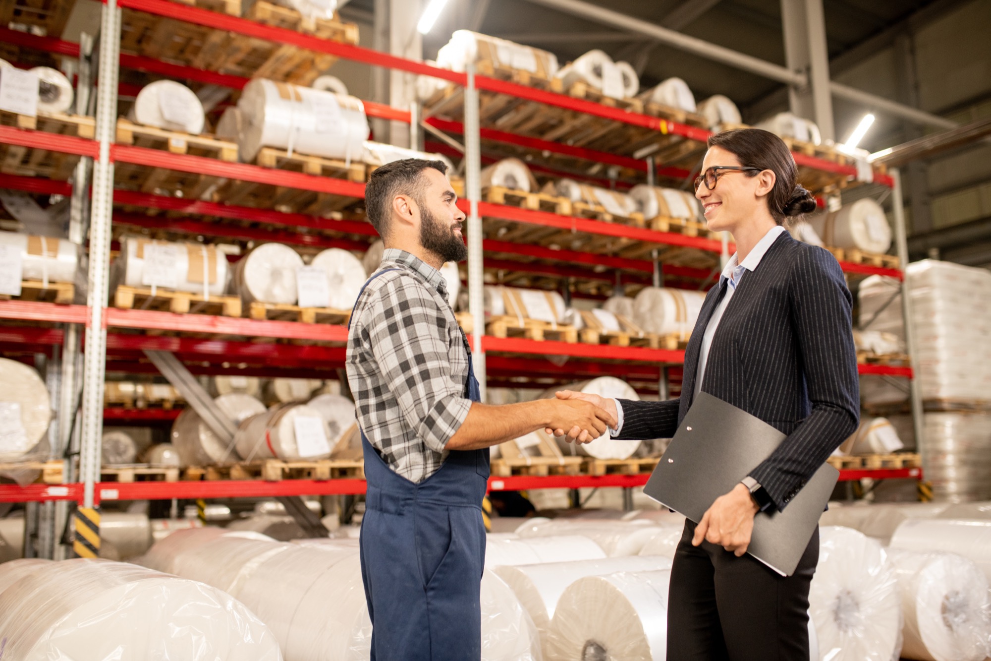 Two business partners shaking hands in a warehouse after a negotiation
