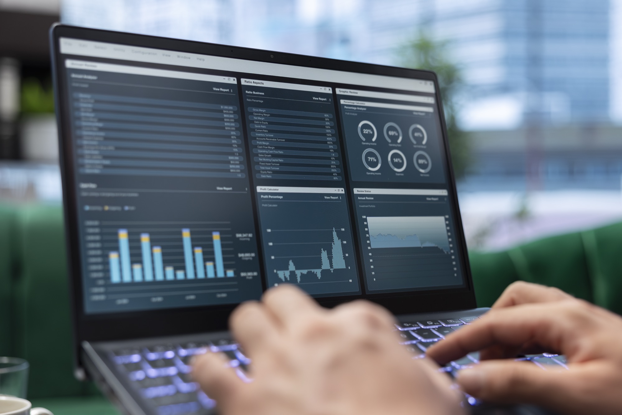 Close-up of hands typing on a laptop displaying data dashboards and charts