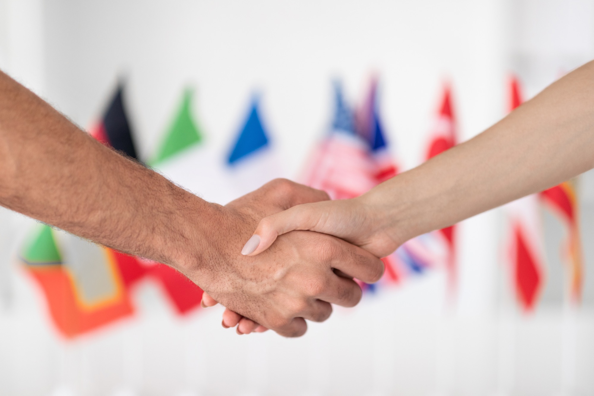 A business handshake with international flags in the background